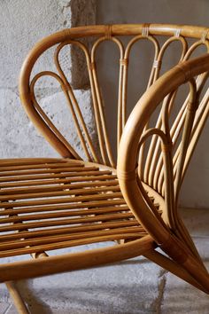 a wicker chair sitting in front of a wall with stone flooring and walls behind it