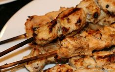 chicken skewers on a white plate with chopsticks