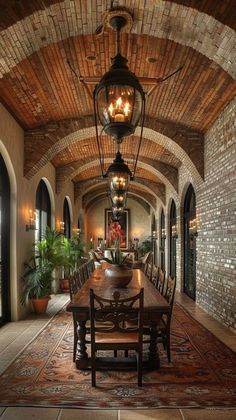 a dining room with a table and chairs in front of a large brick wall that has arched doorways