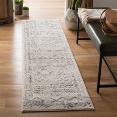 a white rug is on the floor next to a bench and potted plant in a living room