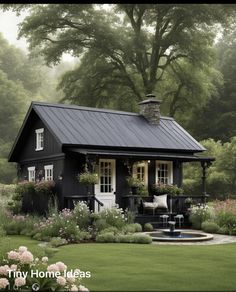 a small black house surrounded by flowers and trees