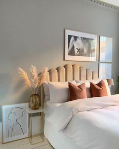 a bed with white sheets and pillows in a bedroom next to pictures on the wall