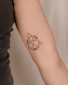 a woman's arm with a tattoo on it that has purple flowers in the center