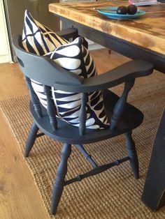 a chair with pillows on it sitting in front of a table