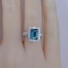 a woman's hand with a ring on it and an emerald stone in the middle