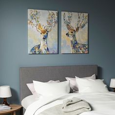 two paintings on the wall above a bed