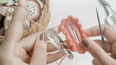 two hands are holding crochet scissors and yarn in front of some knitting needles