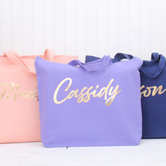 three different colored bags with the word cassedy printed on them, one is pink and one is blue