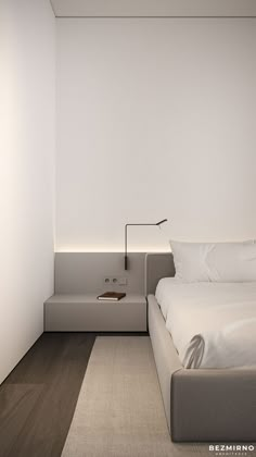 a bed sitting next to a white wall in a bedroom on top of a hard wood floor