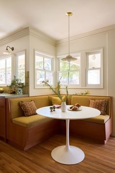 a kitchen with a table, bench and two windows in it's center area