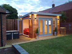 a small wooden shed with lights on the roof and patio furniture in the back yard