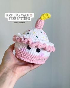 a hand holding a crocheted birthday cake with a hat on it's head