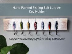 five fishing lures mounted on a wall with text that reads, hand painted fishing lure art key holder unique housewarming gift for fishing enthusiast