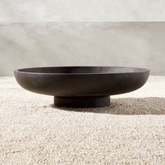 a large black bowl sitting on top of a white floor next to a cement wall