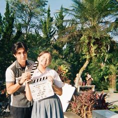 a man and woman standing next to each other holding a clapper in their hands