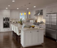 a large kitchen with white cabinets and stainless steel appliances, along with a center island