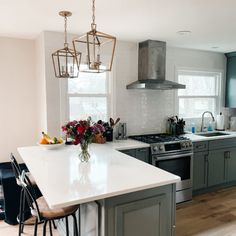 a kitchen with white counter tops and gray cabinets