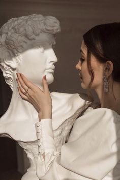 a woman touching the face of a white busturine