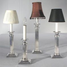 three glass candlesticks with lampshades on them, one black and one white