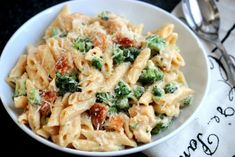 a white bowl filled with pasta and broccoli on top of a tablecloth