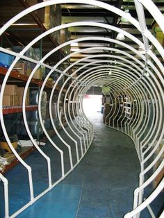 the inside of a large metal tunnel with white railings and shelves on either side