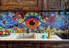 a kitchen counter topped with a sink under a stained glass eyeball mosaic wallpaper