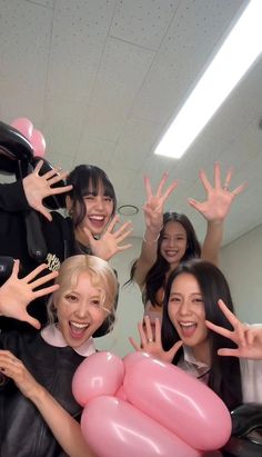 group of young women posing with balloons in the shape of hand signs and smiling at camera