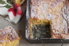 a cake with powdered sugar on top is sitting next to another piece of cake