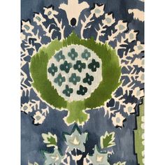 a blue and green rug with white flowers on the center, in front of a black background