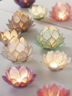 several lit up lotus flowers sitting on top of a white table next to each other