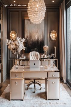 a desk with a laptop on it in front of a large window and chandelier