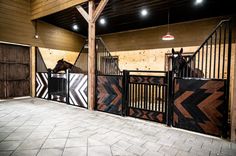 two horses are standing in their stalls at the stable, one is black and white