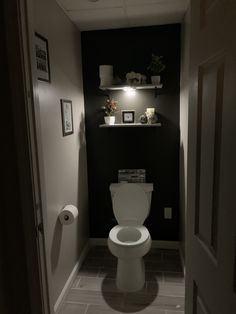 a white toilet sitting inside of a bathroom next to a wall with pictures on it