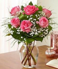 a vase filled with pink roses on top of a wooden table