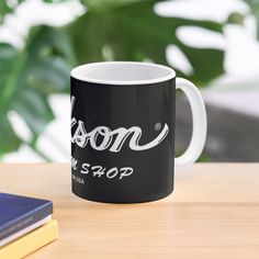 a black and white coffee mug sitting on top of a table next to a book