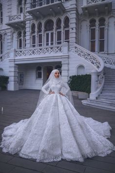 a woman in a white wedding dress standing on the sidewalk outside a large building with stairs