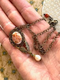 "A vintage Carnelian and filigree  earring no longer has the pin on the back so it has been repurposed into a wonderful pendant necklace. It is antique brass with a 3/4 x 1/2\" oval, faceted Carnelian cabochon.  dangling at the bottom is a lovely Freshwater Pearl.  The 18 1/2\" antique brass, oval link chain also has a 1\" extender chain and closes at the neck with a lobster clasp and small Carnelian dangle This unique, repurposed necklace has a wonderful Victorian feel ♥ Buy Unique. Buy Quality