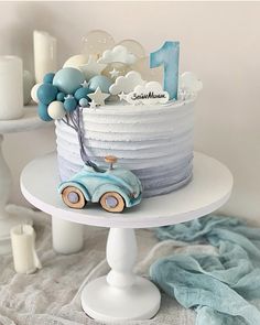 a blue and white birthday cake on a table with candles in the shape of cars