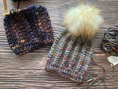 two knitted hats sitting on top of a wooden table