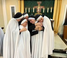 a group of women dressed in nun costumes hugging each other and smiling at the camera