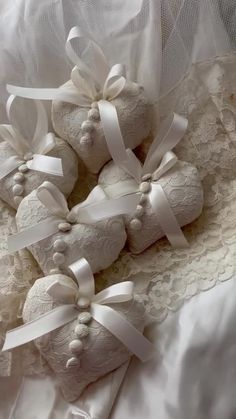 four white teddy bears tied together on a lace covered bed sheet with ribbons and bows