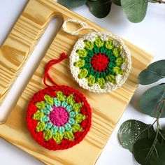 two crocheted ornaments are sitting on a cutting board