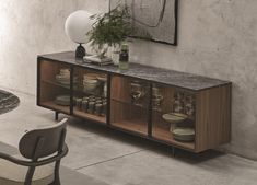 a sideboard with plates and vases on it in front of a wall mounted mirror