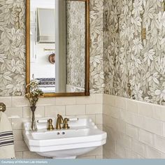 a white sink sitting under a bathroom mirror next to a wall mounted faucet