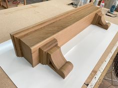 a wooden bench sitting on top of a white sheet in a room with unfinished furniture