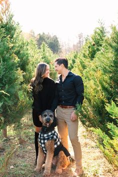 a man and woman standing next to each other with their dog