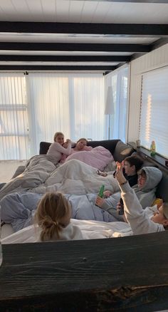 a group of people laying on top of a bed in a living room next to each other