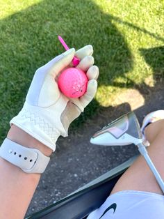 a person wearing white gloves holding a pink golf ball