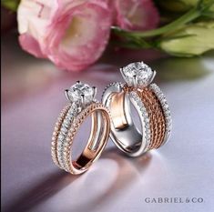 two wedding rings sitting next to each other on a table with flowers in the background