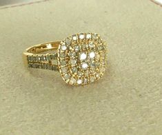 a yellow gold ring with white and brown diamonds on it sitting on a counter top